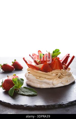 Dessert aux fraises avec feuilles de menthe sur une assiette sombre dans un cadre lumineux Banque D'Images