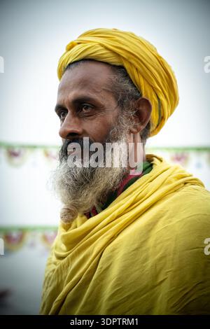 Un portrait réfléchi d'un Sadhu hindou dans un turban jaune vif et des robes à Dashashwamedh Ghat à Varanasi, en Inde. Banque D'Images