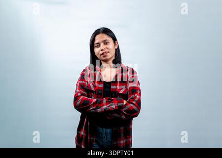 Joyeuse femme asiatique du Sud-est posant avec un sourire amical. Studio isolé tourné sur fond blanc, concept d'étudiant indonésien heureux ou de jeunesse. Banque D'Images