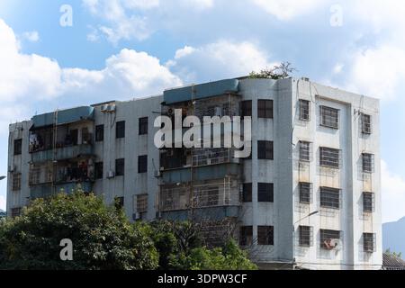 Immeuble d'appartements à plusieurs étages vieilli avec balcons rouillés sous le ciel nuageux dans la zone urbaine Banque D'Images