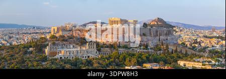 Vue aérienne de l'Acropole, baignée de lumière dorée, se dresse majestueusement sur les ruines antiques et le paysage urbain tentaculaire, Athènes, Athènes centrale R Banque D'Images