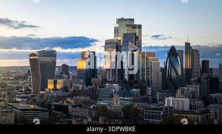 Vue aérienne de gratte-ciel perçant l'horizon, avec des façades en verre reflétant les teintes chaudes du soleil couchant, Londres, Royaume-Uni. Banque D'Images