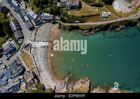 Vue aérienne d'une crique tranquille où la plage de sable rencontre les eaux turquoises, parsemées de bateaux et de kayakistes, tandis que les bâtiments bordent le rivage, Hope CoV Banque D'Images