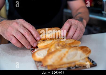 Mains du chef arrangeant de petites baguettes cuites sur le plateau Banque D'Images