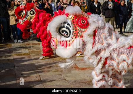 9 février 2024 - Lisbonne, Portugal : spectacle traditionnel de danse du lion chinois avec des lions rouges et blancs divertissant la foule diversifiée sur la place historique de la ville européenne en plein air le jour ensoleillé pour célébrer le nouvel an lunaire. Diversité culturelle, multiculturalisme Banque D'Images