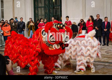 9 février 2024 - Lisbonne, Portugal : spectacle traditionnel de danse du lion chinois avec des lions rouges et blancs colorés divertissant la foule diversifiée sur la place historique européenne en plein air célébrant le nouvel an lunaire et les visiteurs apprécient les événements culturels et les festivités Banque D'Images