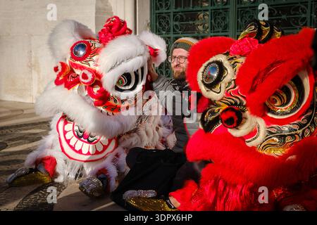 9 février 2024 - Lisbonne, Portugal : spectateur posant pour la photo avec les lions rouges et blancs traditionnels chinois après un spectacle de danse sur la place européenne historique en plein air pendant les célébrations du nouvel an lunaire un jour ensoleillé Banque D'Images