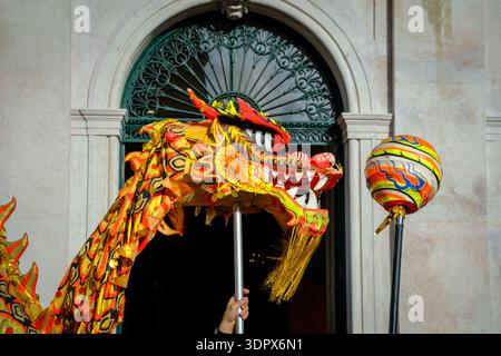 Feb 9, 2024 - Lisbonne, Portugal : papier chinois coloré traditionnel et dragon en tissu se tiennent sur le poteau poursuivant la perle de papier sur le poteau pendant la danse symbolique du Dragon dans les célébrations du nouvel an lunaire dans la ville européenne le jour ensoleillé. La danse apporte sagesse et chance Banque D'Images