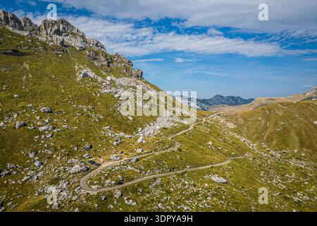Vue aérienne par drone de la route de montagne sinueuse au col de Sedlo dans le parc national de Durmitor, Monténégro, montrant des camping-cars et des voitures garées le long du Banque D'Images