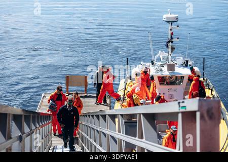 Tadoussac, Canada - 22 août 2025 : des touristes en costumes orange vif embarquent et débarquent de bateaux pneumatiques rigides à la marina de Tadoussac avant un wh Banque D'Images