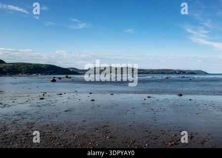 Paysages à marée basse le long des plages de la Baie Sainte Catherine avec rivage sablonneux et galets, eau peu profonde calme, rochers éparpillés et colline boisée Banque D'Images