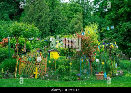 Jardin créatif lumineux avec nichoirs, fleurs et décorations faites à la main. Verdure luxuriante et couleurs vibrantes dans un cadre confortable arrière-cour. Banque D'Images