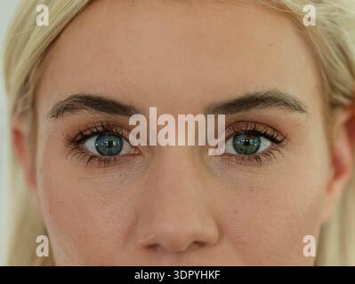 Femme regardant calmement en studio gros plan, montrant fard à paupières en cuivre, mascara, texture de peau Banque D'Images