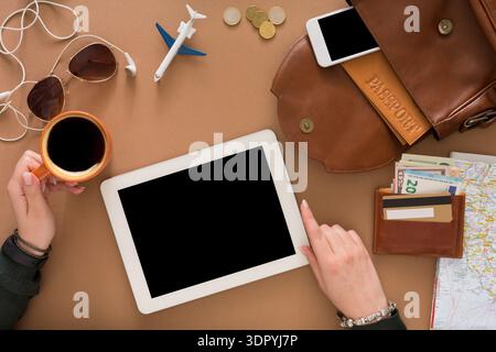 Planification de voyage avec des appareils et des éléments essentiels sur une table dans un cadre décontracté Banque D'Images