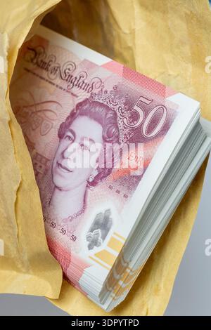 Gros plan d'une enveloppe marron contenant une pile de billets de cinquante livres. Banque D'Images