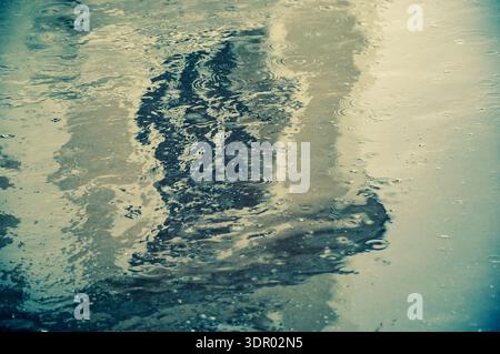 La vieille maison se reflète dans la flaque d'eau sur le trottoir dans les jours de pluie. Flou. Rétro. Sélectionnez Focus sur les ondulations de l'eau. Banque D'Images