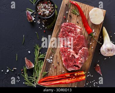Coupe fraîche de bœuf avec des herbes et des épices sur planche en bois dans le cadre de la cuisine Banque D'Images