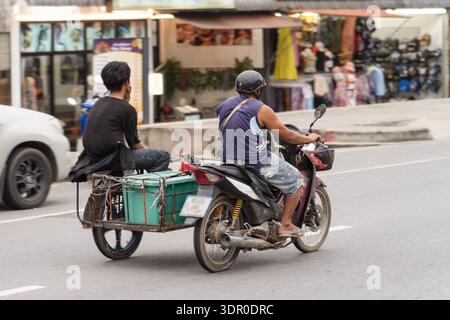 Khaolak Thaïlande 2025 11 24 : une moto avec un side-car dans la rue roule le long de la rue d'une ville provinciale thaïlandaise. La vraie vie en Thaïlande dans le Banque D'Images