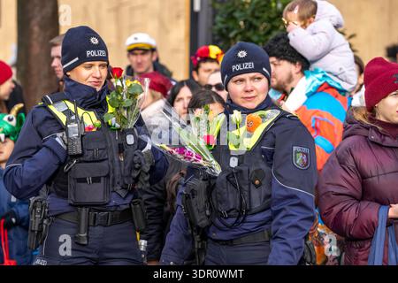 Rosenmontagszug in Düsseldorf, Einsatzkräfte, sichern, begleiten den Umzug, Polizistin mit geschenkten Blumen Sträußchen, Strüsschen, BEI teils starkem Regen, NRW, Deutschland Rosenmontag dus *** Rosenmontag parade in Düsseldorf, services d'urgence, sécuriser, accompagner la parade, policière avec bouquets de fleurs, bouquets, sous une pluie partiellement forte, NRW, Allemagne Rosenmontag dus Banque D'Images