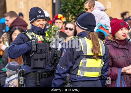 Rosenmontagszug in Düsseldorf, Einsatzkräfte, sichern, begleiten den Umzug, Polizistin mit geschenkten Blumen Sträußchen, Strüsschen, BEI teils starkem Regen, NRW, Deutschland Rosenmontag dus *** Rosenmontag parade in Düsseldorf, services d'urgence, sécuriser, accompagner la parade, policière avec bouquets de fleurs, bouquets, sous une pluie partiellement forte, NRW, Allemagne Rosenmontag dus Banque D'Images
