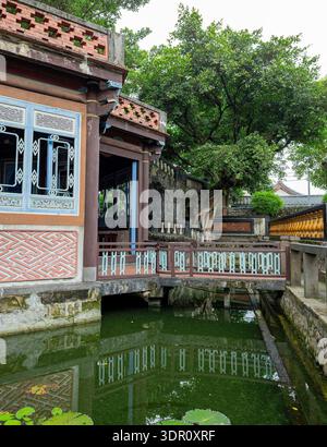 Le pavillon chinois traditionnel avec des balustrades bleues et rouges se reflète dans l'étang calme. Banque D'Images