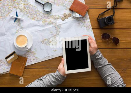 Planifier un voyage avec une tablette, un café et des documents de voyage dans une pièce lumineuse Banque D'Images