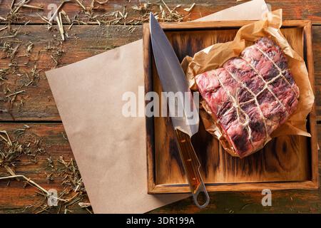 Viande fraîche coupée reposant sur une planche en bois avec un couteau à côté sur une table rustique Banque D'Images