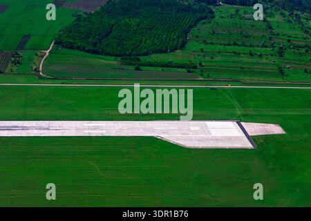 La prise de vue aérienne capture une piste en béton. L'aérodrome est entouré de vastes champs verdoyants et de denses parcelles de forêt, caractéristiques de son pays rural Banque D'Images