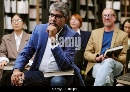 Homme d'Asie du Sud d'âge moyen écoutant attentivement pendant l'événement de présentation de livre Banque D'Images