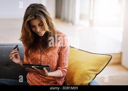 Femme heureuse, achats en ligne et services bancaires avec tablette pour le paiement ou l'achat à la maison. Personne féminine, acheteur ou sourire avec débit ou technologie pour Banque D'Images