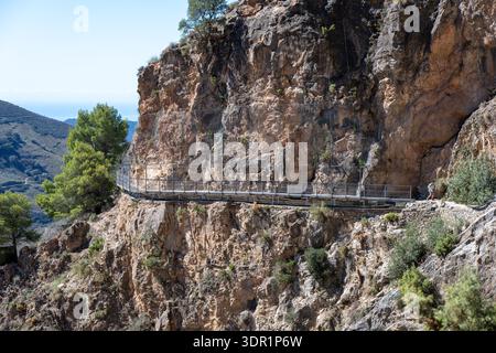 Passerelle métallique attachée à une paroi rocheuse escarpée sur le sentier El Saltillo dans la province de Málaga, Andalousie, Espagne, avec garde-corps de sécurité et filet au-dessus du c Banque D'Images