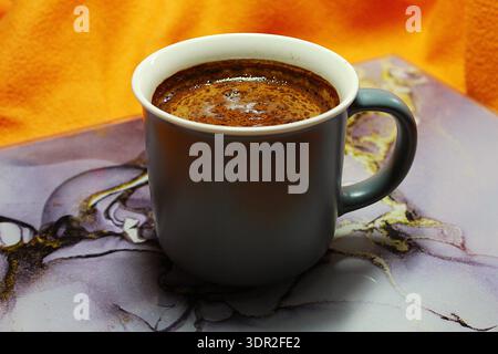 Gros plan d'une tasse en céramique grise remplie de café noir chaud. Banque D'Images