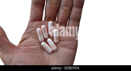Vue de haut en bas d'une paume ouverte tenant plusieurs pilules de capsule médicale rose clair isolées sur fond blanc. Imagerie de santé professionnelle pour pharmaceu Banque D'Images