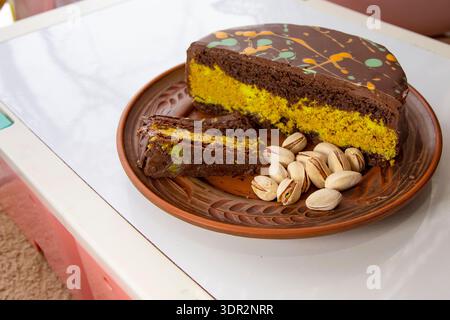 Tranche de gâteau de couche de pistache de chocolat sur plaque de céramique avec des pistaches entières Banque D'Images