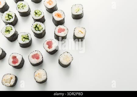 Différents types de sushi disposés sur une surface blanche lors d'une présentation alimentaire Banque D'Images