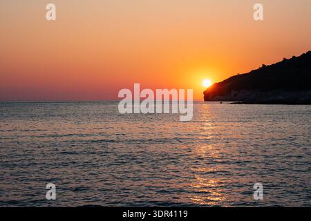 Vue du soleil plongeant sous l'horizon, peignant la mer avec des teintes flamboyantes alors qu'elle rencontre la silhouette sombre de la côte, Pula, Croatie. Banque D'Images