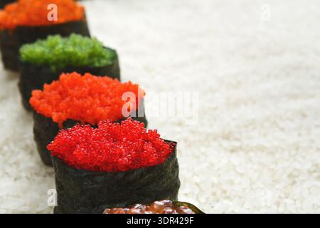 Différents types de Sushi Rolls avec des garnitures colorées disposées sur un lit de riz Banque D'Images