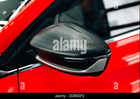 Gros plan montre un miroir en fibre de carbone sur une voiture de luxe rouge Banque D'Images