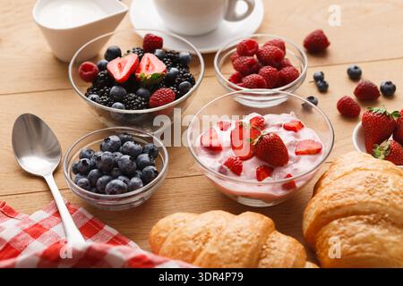 Breakfast Collection avec baies, yaourts et croissants sur une table en bois Banque D'Images