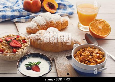 Petit-déjeuner collage avec viennoiseries, fruits et céréales sur une table en bois avec une boisson Banque D'Images