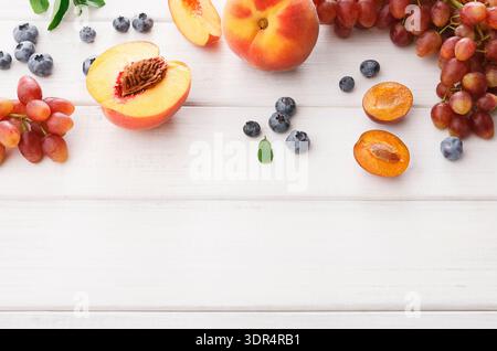 Collage de fruits, y compris des pêches, des raisins et des bleuets sur une table en bois Banque D'Images