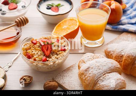 Collage petit-déjeuner avec fruits, yaourt et pâtisseries sur la table à l'heure du repas du matin Banque D'Images