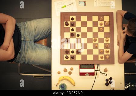 Une vue aérienne de deux joueurs à un tournoi d'échecs, mettant l'accent sur la planche de bois, les pièces en jeu, un chronomètre numérique et une collation à la banane Banque D'Images