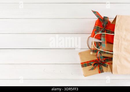 Présentation de cadeau avec des boîtes emballées et un sac à provisions sur une surface en bois clair Banque D'Images