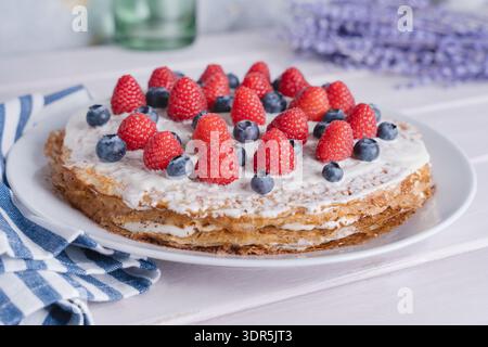 Vue large de gâteau à crêpe maison en couches avec de la crème et de la chapelure de chocolat, garni de framboises et de myrtilles, style provençal, gâteau entier Banque D'Images