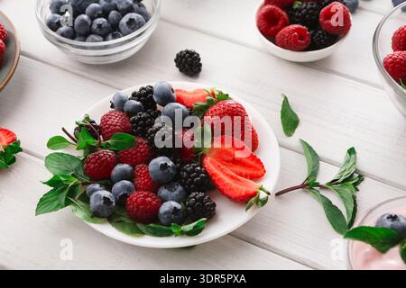Collection de fruits frais affiché dans des bols sur une table en bois pendant un après-midi ensoleillé Banque D'Images