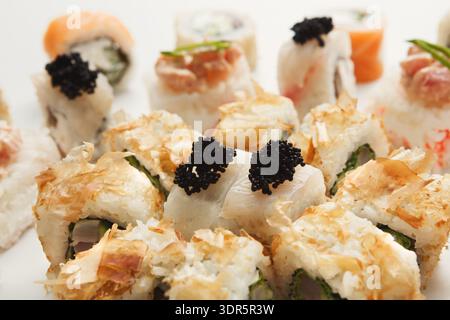 Rouleaux de Sushi frais sur une assiette blanche avec des garnitures colorées dans un cadre lumineux Banque D'Images