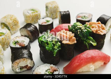 Variété de Sushi servis sur une assiette blanche avec différentes garnitures de poisson et de légumes Banque D'Images