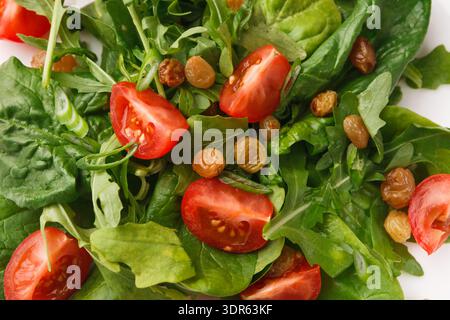 Salade fraîche mélangée avec des légumes verts, des tomates et des raisins secs disposés sur une assiette Banque D'Images