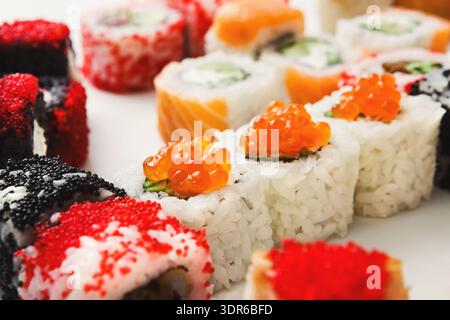 Rouleaux de sushi avec garnitures colorées disposées sur une assiette blanche pour un affichage de repas Banque D'Images